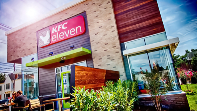 Outdoor image of a KFC eleven with bright greenery lining the walk into the store