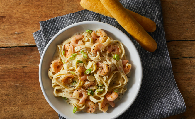 Fettuccini Alfredo with Shrimp on top and breadsticks on the side